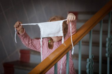 Çocuk yüzünden koruyucu bir tıbbi maske çıkarıyor..