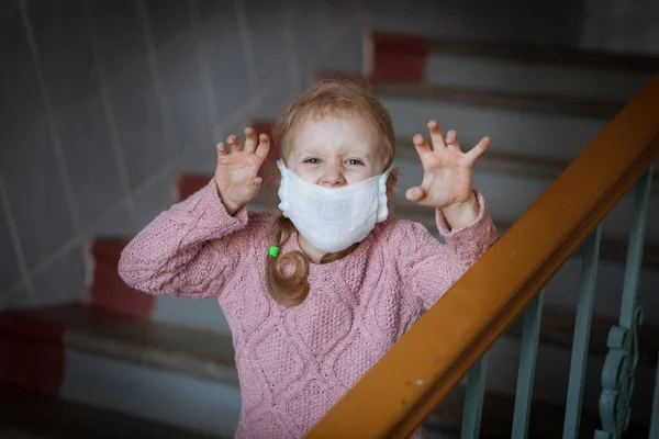 Kız çocuğu üzgün, yüzünde virüse karşı tıbbi bir maske var..