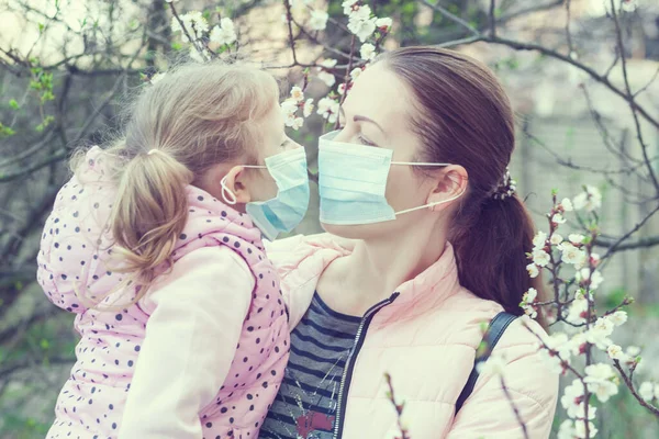 Daughter and mother wearing masks on the street. Pandemic virus.