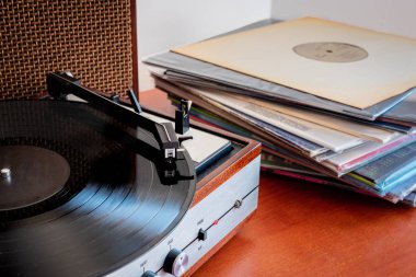 Eski bir masanın üzerinde vinylelarla yapılmış eski bir pikap. 