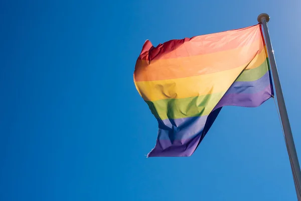 LGBT pride flag waving in the blue sky