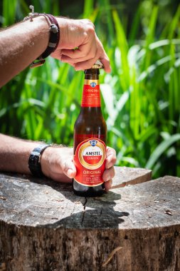 Ülkede Amstel bira şişesi açan bir adam.