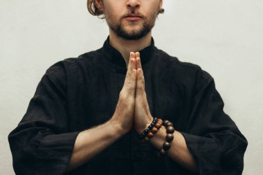 Siyah gömlekli bir adam avuç içlerini kavuşturup yoga yapıyordu. Ellerin duayla bağlandı. Ellerini birleştir. Dua, şükran. Yoga el pozu. Katlanmış eller. Avuç içi. Kapat.