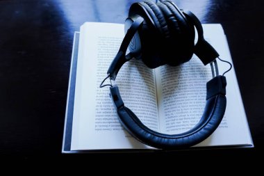 Auriculares y libro en fondo marron de madera