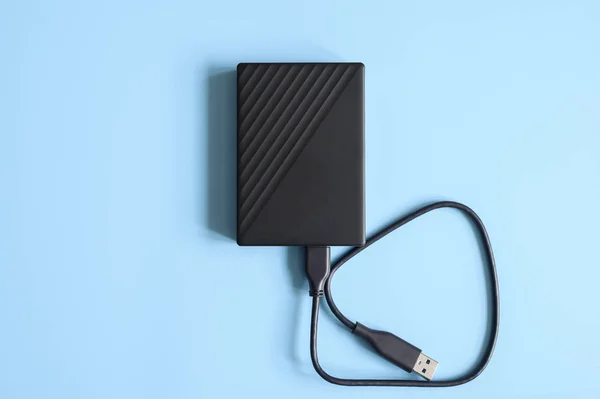 external hard drive black color with connection cable on blue background