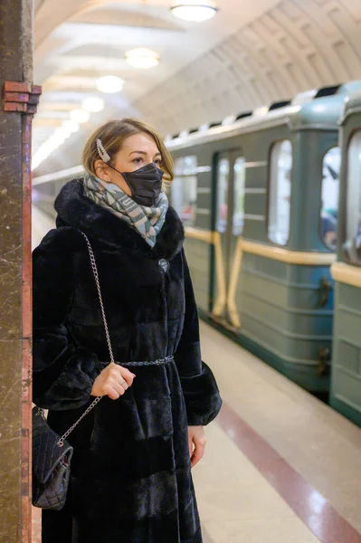 young european woman in protective disposable medical black mask in metro. concept protection of dangerous 2019-nCoV influenza coronavirus, mutated and spreading in China. vertical photo