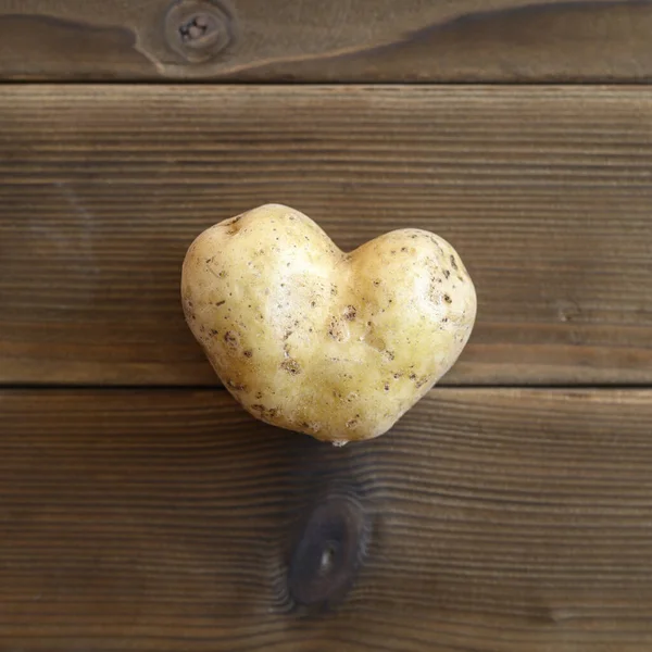 ugly food. an ugly vegetable a heart shaped potato on a wooden plank table. square