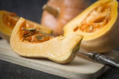 Koyu bir zemin üzerinde güzel olgun balkabakları, dilimlenmiş ve bütün.