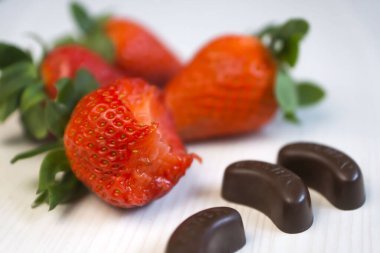 Taze, olgun, güzel, çilek. Çikolata şekerler ve çilekler tepeden görünüyor..