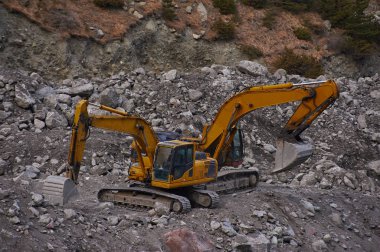 Two excavators digging ground together