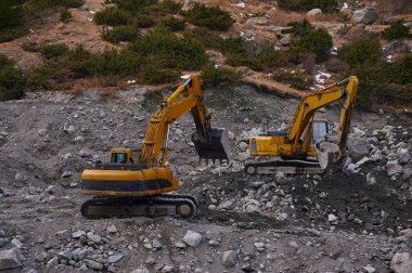 Two excavators digging ground together