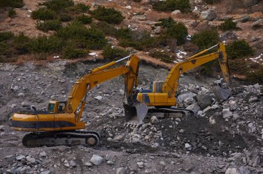Two excavators digging ground together
