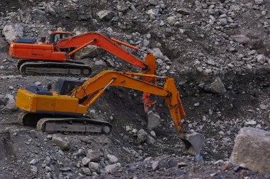 Two excavators digging ground together