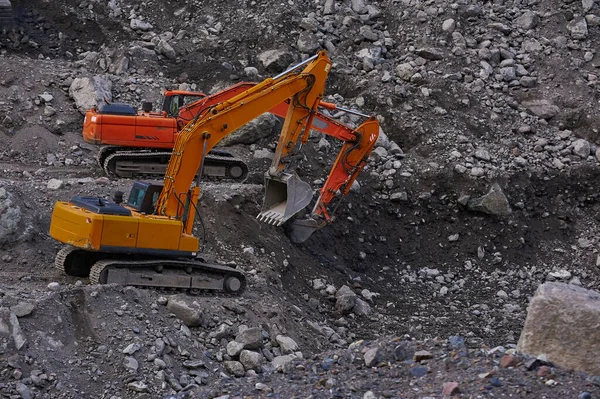 Two excavators digging ground together