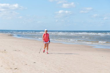 Elderly lady walking on sandy beach at Baltic Sea