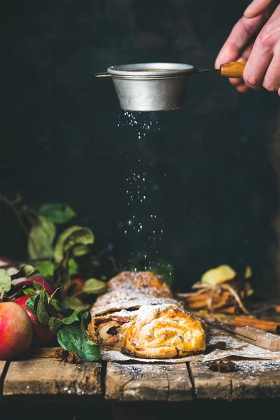 Mãos de homem polvilhando açúcar em pó no bolo de strudel de maçã — Fotografia de Stock
