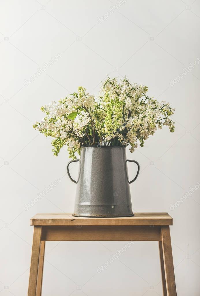 white lilacs in vintage enamel vase