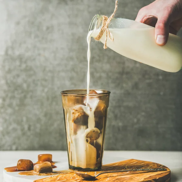 Hand pouring milk to latte cocktail — Stock Photo, Image