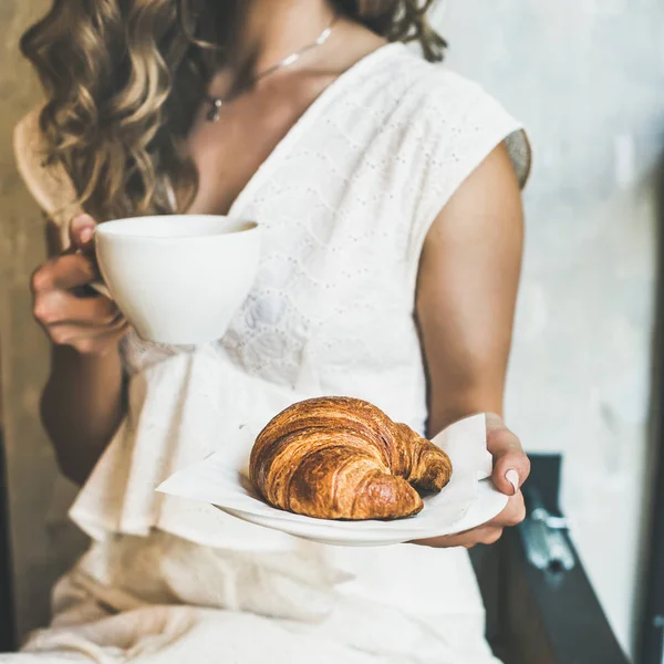 Vrouw bedrijf croissant en cappuccino — Stockfoto