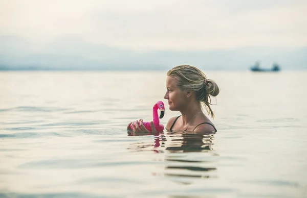 Mulher nadando com flamingo brinquedo — Fotografia de Stock