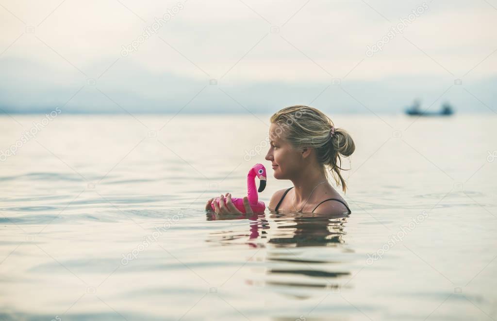 woman swimming with flamingo toy