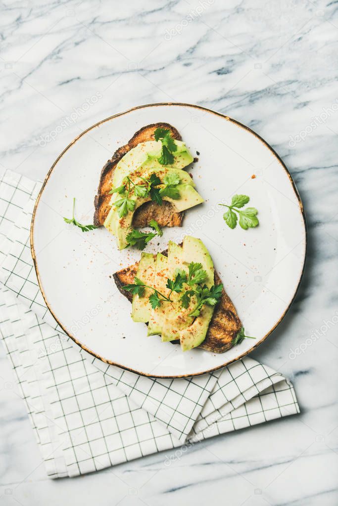 Healthy vegan breakfast or lunch. Flat-lay of avocado toast on plate over grey marble background, top view. Clean eating, detox, weight loss, vegetarian, dieting food concept
