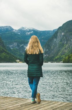 Female traveler standing at mountain lake clipart