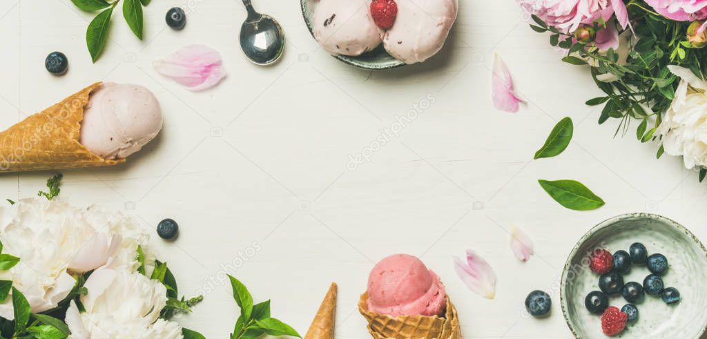 Pink strawberry and coconut ice cream scoops, sweet cones and peony flowers bouquet over white background