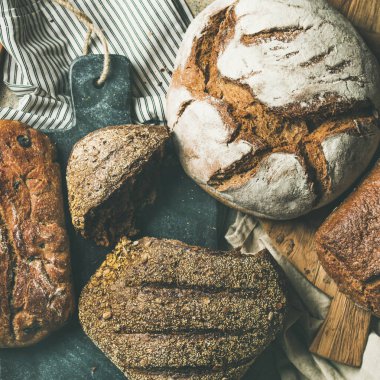 Çeşitli seçim ekmek. Çavdar, buğday ve buğday rustik ekmek somunları mutfak havlu ve gri Beton taş arka plan üzerinde ahşap panoları