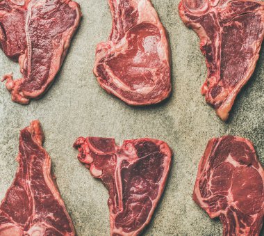Taze çiğ çiğ sığır eti biftek gri beton arka plan üzerinde en iyi görünümü keser. Porterhouse, t-bone ve kaburga biftek