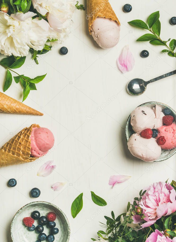 Pink strawberry and coconut ice cream scoops, sweet cones and peony flowers bouquet over white background