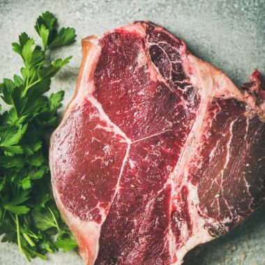 Ham pişmemiş kuru yaşlı t-bone sığır eti biftek taze yeşil maydanoz ile Başbakan ve tuz metal arka plan üzerinde füme