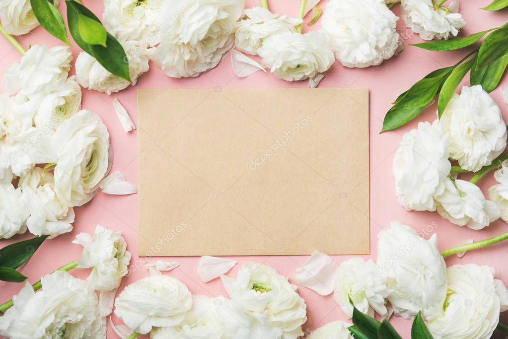 Saint Valentines Day frame or background. White ranunculus flowers and sheet of paper over light pink background