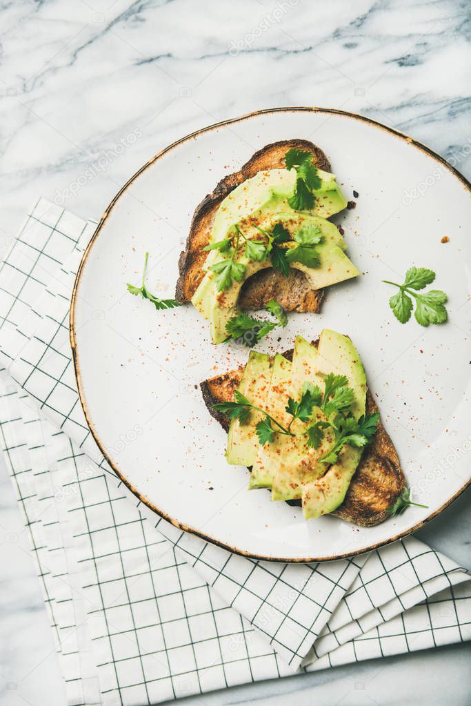 Healthy vegan breakfast or lunch. Avocado toast on plate over grey marble background