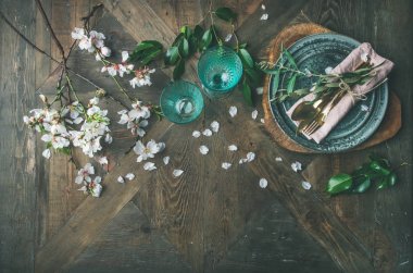 Düz-lay bahar Paskalya tatili Tablo ayarı. İhale badem çiçeği çiçek dalları, tabaklar, gözlük ve çatal bıçak takımı vintage ahşap masa arka plan, üstten görünüm, kopya alanı