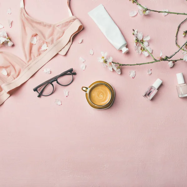 Womans morning rituals concept. Feminine tender powder color lingerie, glasses, cosmetic items, cup of coffee and Spring blossom flowers over pastel pink bed cover — Stock Image Womans Morning Rituals Concept Feminine Tender Powder Color Lingerie Glasses Royalty Free Stock Images