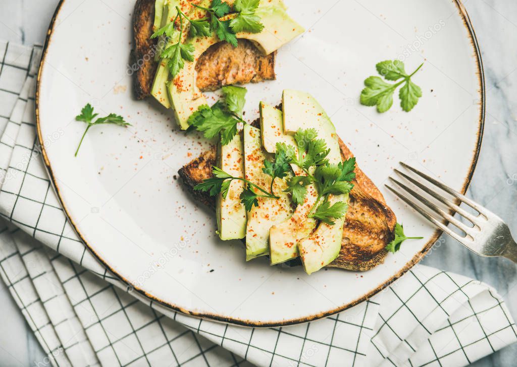 Healthy vegan breakfast or lunch. Avocado toast on plate over marble background