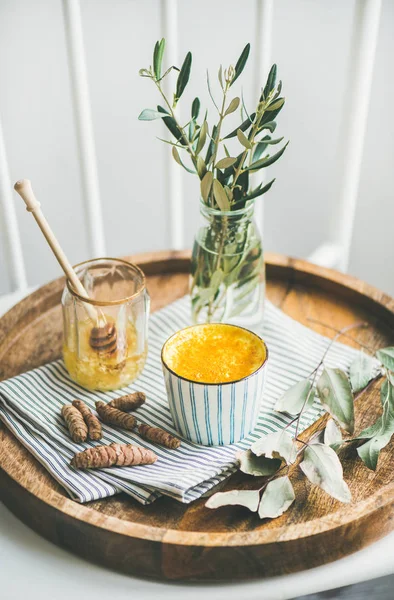 健康な菜食主義者ウコン ラテや木製トレイにストライプのカップに蜂蜜とゴールデン ミルク — ストック写真
