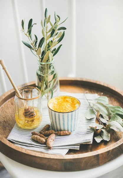健康素食姜黄拿铁或金牛奶与蜂蜜在杯子在木托盘 — 图库照片