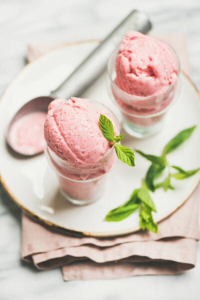 Healthy low calorie summer dessert. Homemade strawberry yogurt ice cream in glasses over light grey marble table background