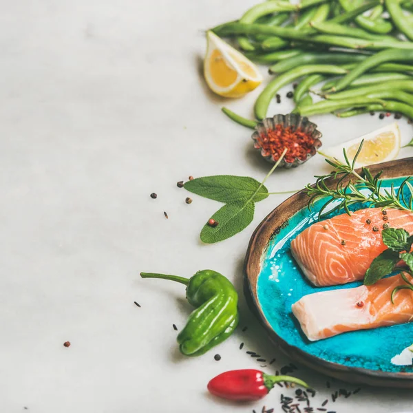 生三文鱼鱼片牛排配蔬菜 香料和柠檬在蓝色的盘子上 在浅灰色大理石背景 — 图库照片