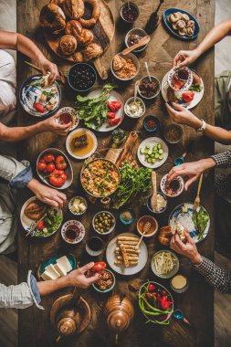 Türk kahvaltısı. Hamur işleri, sebzeler, yeşiller, peynirler, sahanda yumurtalar, doğu sofra takımında reçeller, lale bardaklarında çay ve kırsal ahşap arka planda yaşayan insanlar.