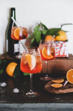 Aperol Spritz aperatif soğuk içecek bardaklarda portakal ve buz küpleriyle beton masa, beyaz arka plan, seçici odak. Yaz ferahlatıcı içecek konsepti