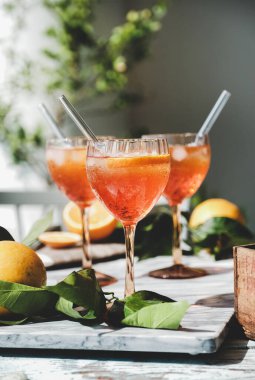 Portakallı bardaklarda Aperol Spritz aperatif alkol soğuk içecek ve gri mermer tahtada buz, seçici odaklanma. Yaz ferahlatıcı içecek konsepti