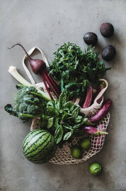 Sağlıklı sebze ürünleri. Gri mutfak tezgahının üzerinde yerel çiftçi pazarından sebze, meyve ve sebze dolu düz bir çanta, üst manzara. Çevre dostu, sıfır atık, temiz yemek, vegan konsept