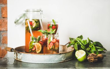 Taze ev yapımı çilek ve fesleğenli limonata ya da cam kavanozlarda buzlu çay kırsal metal tepside çevre dostu plastik pipetler, arka planda beyaz duvar, kopyalama alanı. Yaz ferahlatıcı meşrubat