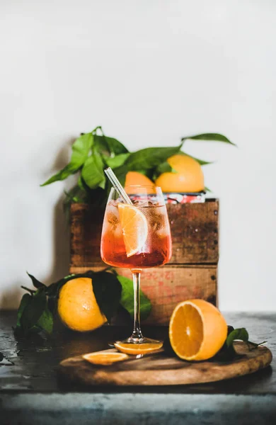 Aperol Spritzは コンクリートテーブルの上に環境に優しいガラスストロー 背景の白い壁 コピースペースのあるガラスの中にオレンジと氷のキューブと冷たい飲み物を食前酒を食前酒します 夏の爽やかなドリンクコンセプト — ストック写真