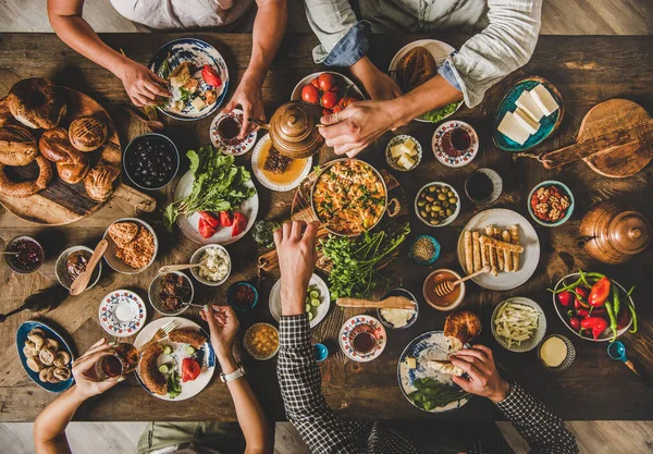 トルコ式朝食 ペストリー グリーン チーズ 目玉焼き 東洋の食器からのジャム 素朴な木製の背景にチューリップグラスからのお茶を飲む トップビューを食べる家族のフラットレイ — ストック写真
