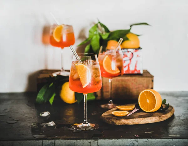 Aperol Spritzは コンクリートテーブル 背景の白い壁に新鮮なオレンジと氷のキューブを持つガラスの中でアルコール冷たい飲み物を食前酒 夏の爽やかなドリンクコンセプト — ストック写真