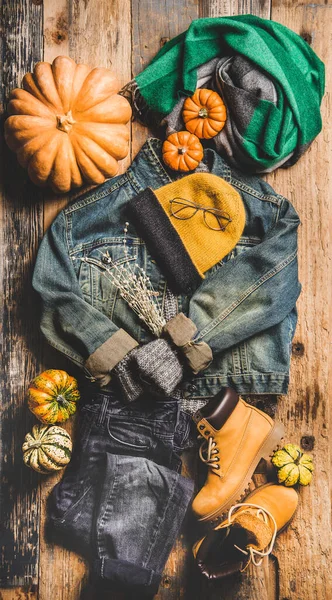 秋の衣装レイアウト ヴィンテージデニムジャケット セーター ジーンズ ウールスカーフ 黄色のブーツ カボチャ キャンドル 木製の背景 トップビュー上のカップでお茶のフラットレイ — ストック写真